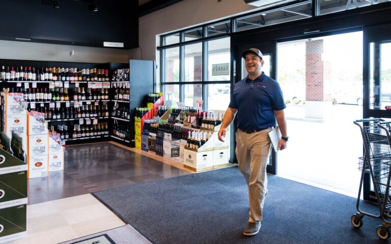 A liquor store employee walks into his store, excited about his liquor store marketing
